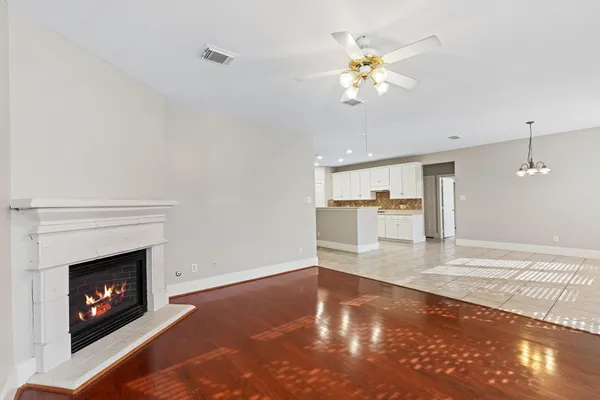 a view of an empty room with a fireplace and chandelier fan