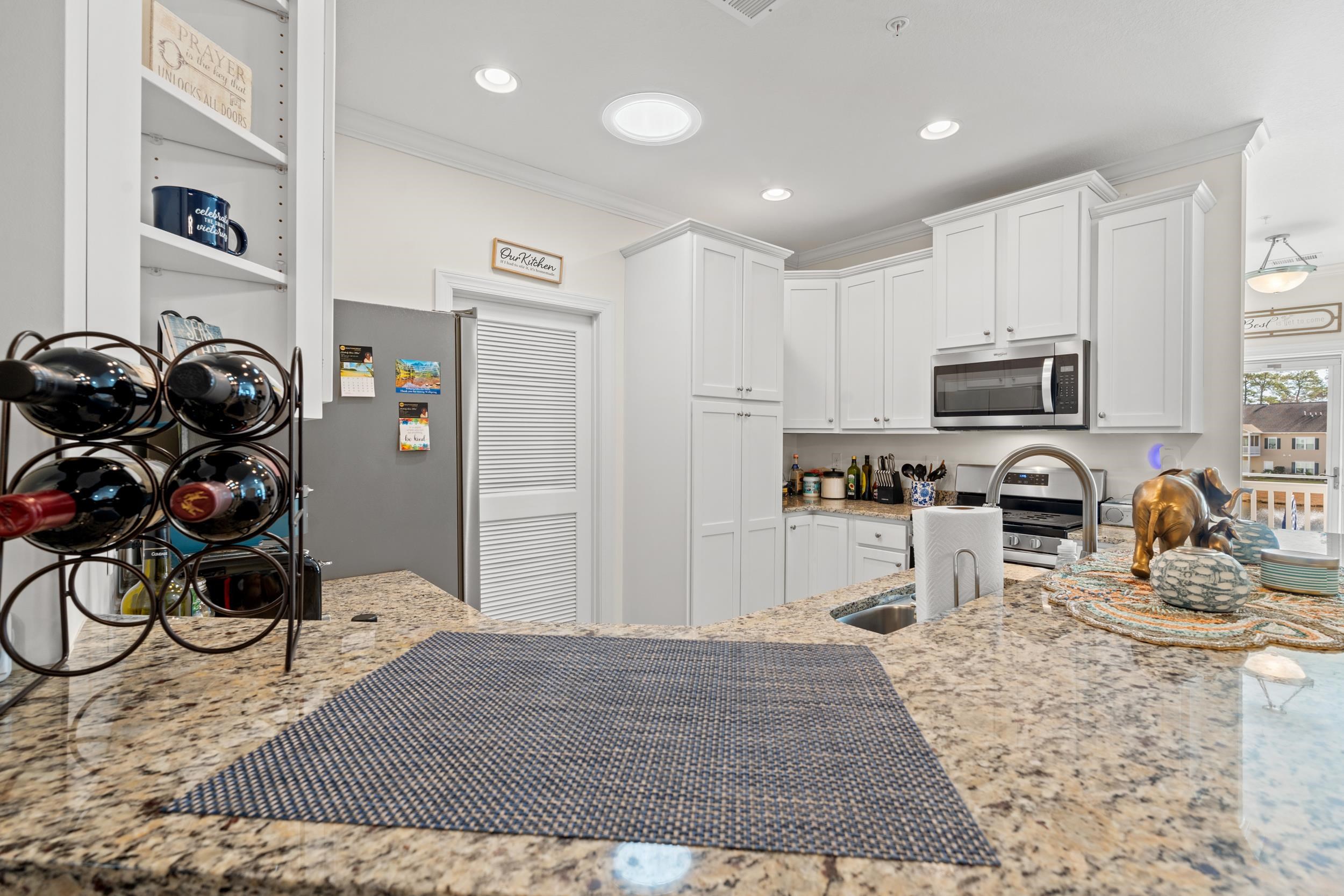900 Jackline Place, Unit 202 Columbia, SC 29209 - Photo 3 of 39 Kitchen with light stone countertops, white cabinetry, stainless steel microwave, recessed lighting, and crown molding