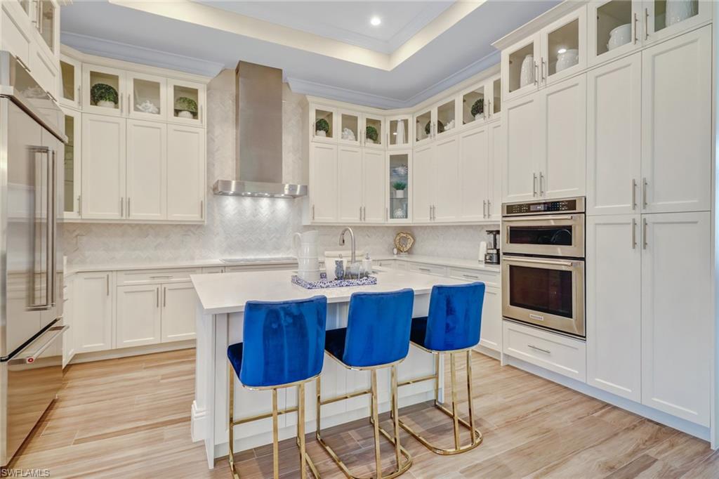 2875 Coco Lakes Drive Naples, FL 34105 - Photo 5 of 27 a kitchen with stainless steel appliances kitchen island granite countertop a kitchen island and chairs in it