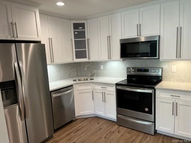 a kitchen with white cabinets stainless steel appliances and wooden floors
