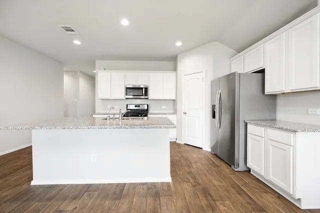 a kitchen with kitchen island a refrigerator sink and wooden cabinets
