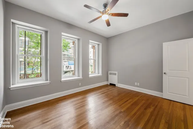 a view of an empty room with a window and wooden floor
