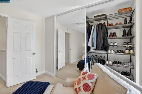 a walk in closet with clothes and shoes