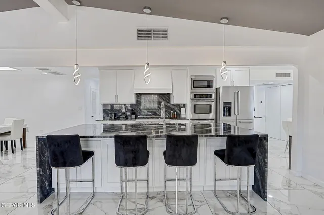 a very nice looking dining room with a dining table a mirror and a chandelier