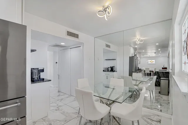 a dining hall with stainless steel appliances kitchen island granite countertop a table and chairs in it