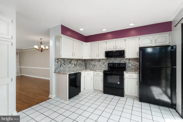 a kitchen with granite countertop a refrigerator and a stove top oven