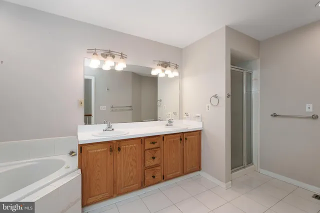 a spacious bathroom with a double vanity sink mirror and bathtub