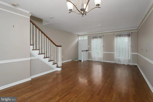 a view of an empty room with wooden floor and stairs