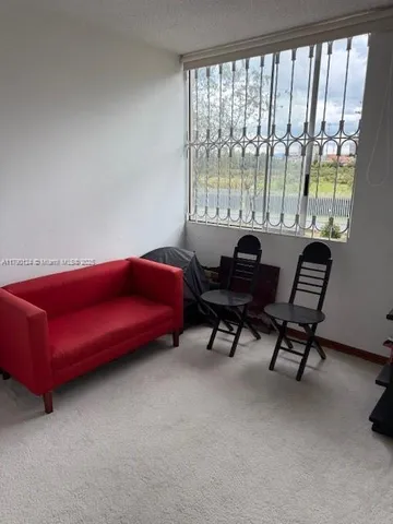 a living room with furniture and a floor to ceiling window
