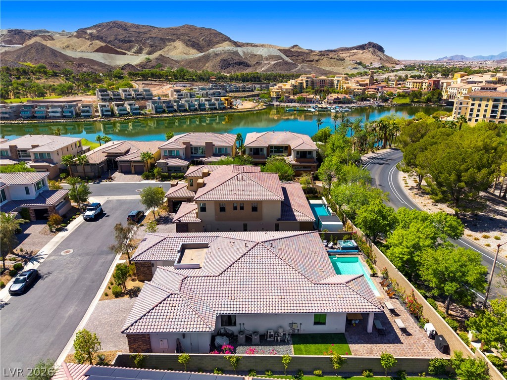 45 Garibaldi Way Henderson, NV 89011 - Photo 42 of 74 An aerial perspective reveals a vibrant community nestled by a serene lake, framed by distant mountains.
