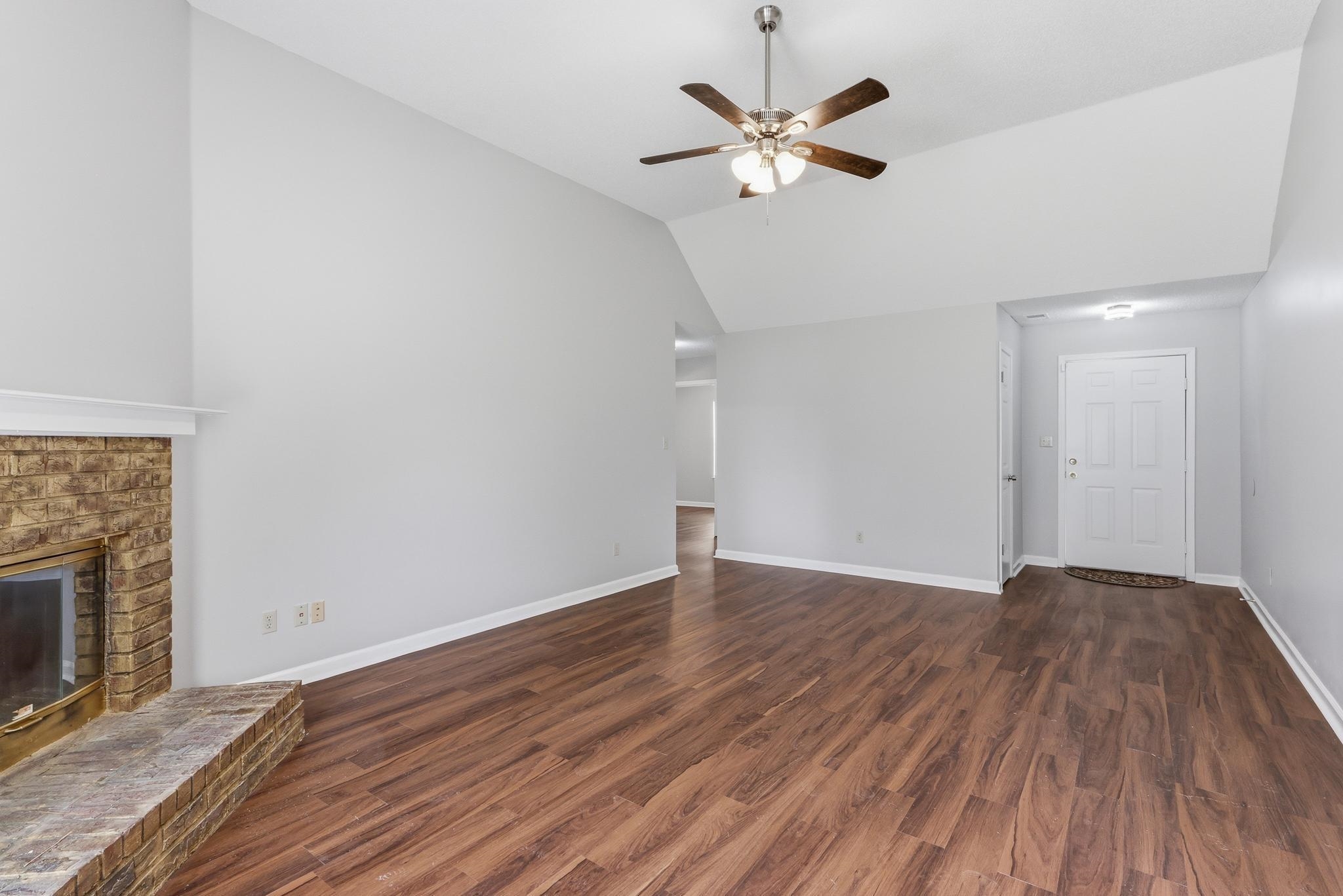4101 Long Creek Road Memphis, TN 38125 - Photo 8 of 36 Spacious living area featuring wood-finish flooring, a brick fireplace with hearth, and vaulted ceilings