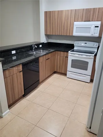 a kitchen with granite countertop a stove a sink and a microwave