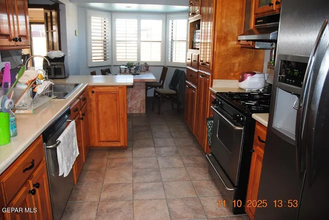 a kitchen with stainless steel appliances granite countertop a refrigerator a stove and a sink