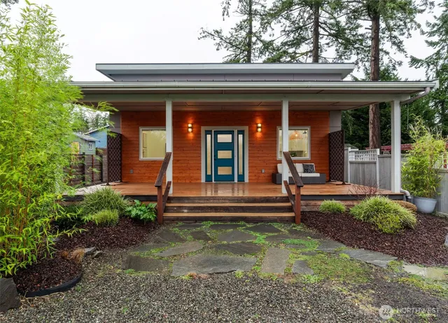 a view of a house with potted plants and a large tree