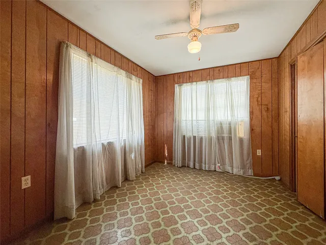 an empty room with windows and a chandelier fan