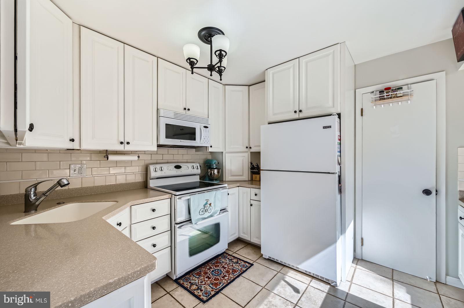 14629 Hanover Pike Upperco, MD 21155 - Photo 12 of 38 a kitchen with granite countertop a refrigerator a sink a stove and white cabinets