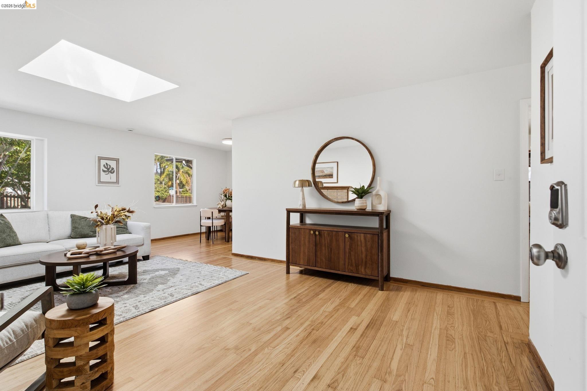 Expansive room featuring a skylight, light wood-finish flooring, and multiple windows