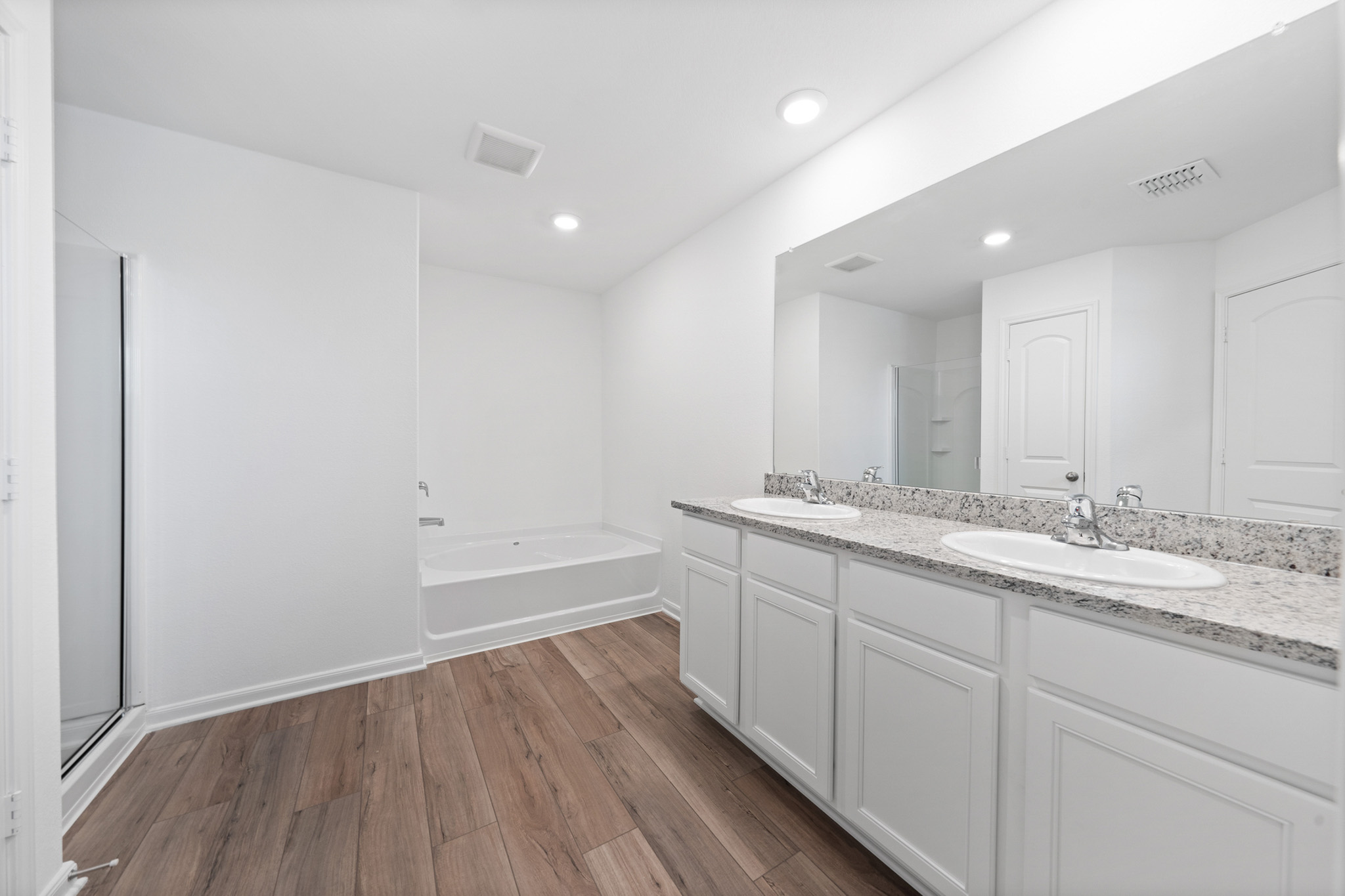 409 Silent Meadow Run Maxwell, TX 78656 - Photo 7 of 10 Bathroom with double vanity, dark wood-style flooring, a stall shower, a garden tub, and recessed lighting