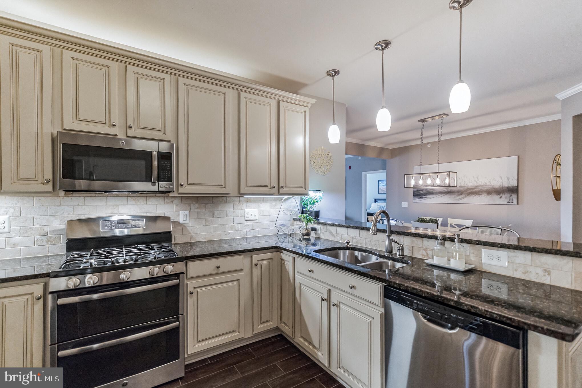 a kitchen with stainless steel appliances granite countertop a sink a stove oven a microwave and cabinets
