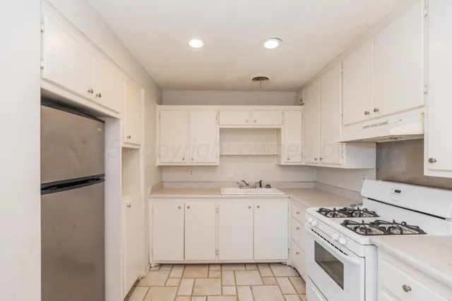 a kitchen with white cabinets and appliances
