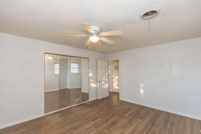 an empty room with wooden floor and a ceiling fan