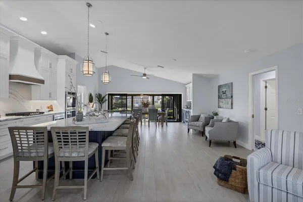 a view of a dining room and livingroom with furniture wooden floor a rug a flat screen tv a rug and a chandelier