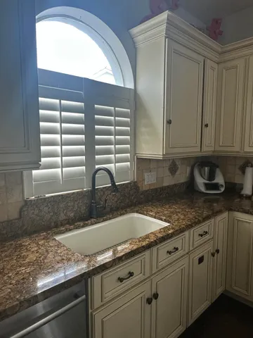 a kitchen with granite countertop white cabinets and a sink