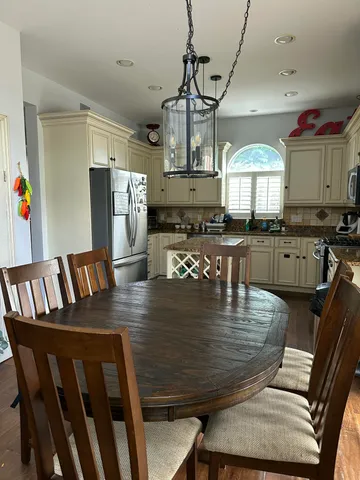 a kitchen with stainless steel appliances granite countertop a stove top oven a dining table and chairs