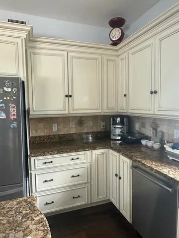 a kitchen with granite countertop a sink cabinets and stainless steel appliances