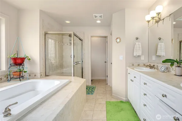 a spacious bathroom with a tub sink and a mirror