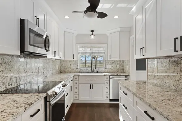a kitchen with stainless steel appliances granite countertop a sink and dishwasher a stove top oven with wooden floor