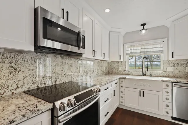a kitchen with stainless steel appliances granite countertop a stove a sink and a microwave