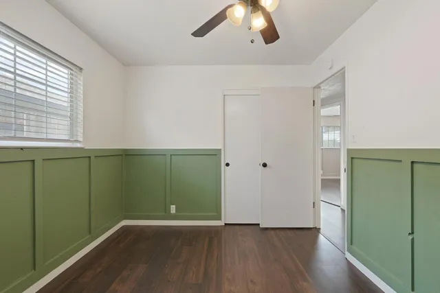 an empty room with wooden floor closet and windows