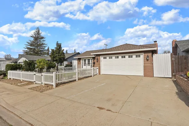 a view of a white house with a large tree