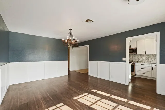 a view of a hallway with wooden floor and chandelier