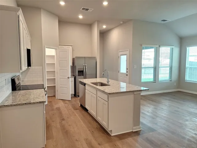 a large kitchen with stainless steel appliances granite countertop a large counter top and a stove top oven