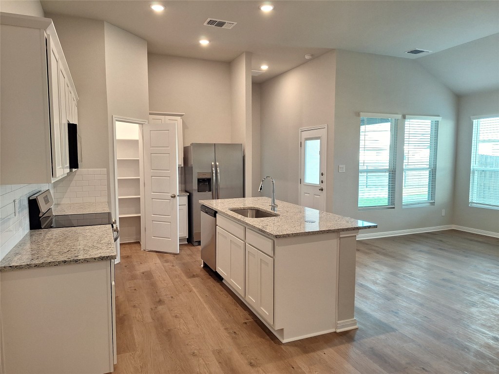 104 Gunner Road, Unit B Buda, TX 78610 - Photo 6 of 22 a large kitchen with stainless steel appliances granite countertop a large counter top and a stove top oven