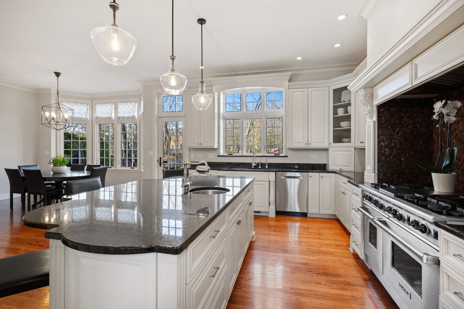 1435 Tower Road Winnetka, IL 60093 - Photo 16 of 34 a large kitchen with stainless steel appliances granite countertop a stove a sink dishwasher a dining table and chairs with wooden floor