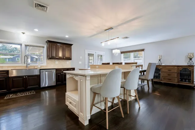 a kitchen with stainless steel appliances kitchen island granite countertop a stove a sink a dining table and chairs