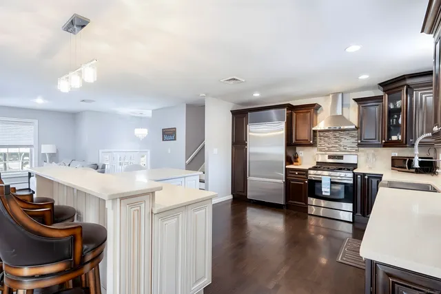 a kitchen with stainless steel appliances kitchen island granite countertop a stove top oven a sink a dining table and chairs with wooden floor