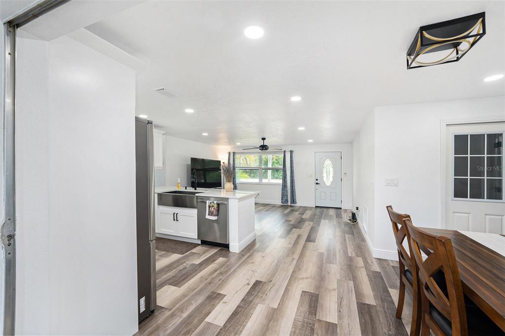 1806 North Keene Road Clearwater, FL 33755 - Photo 17 of 35 a kitchen with stainless steel appliances kitchen island granite countertop a refrigerator a stove a sink a dining table and chairs with wooden floor