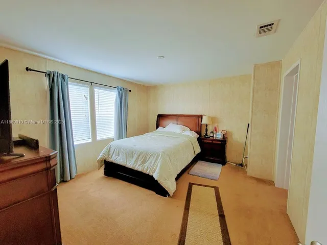 a bedroom with a bed and a flat tv screen on dresser