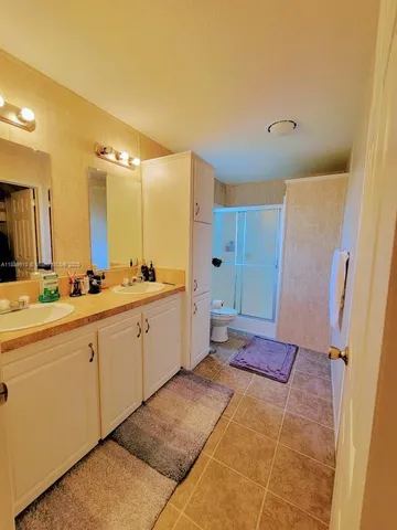 a spacious bathroom with a double vanity sink a mirror and a shower