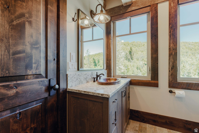1667 West Tollgate Cyn Road Coalville, UT 84017 - Photo 38 of 61 Bathroom vanity featuring a vessel sink, stone countertop, wood-finish cabinetry, and framed mirror