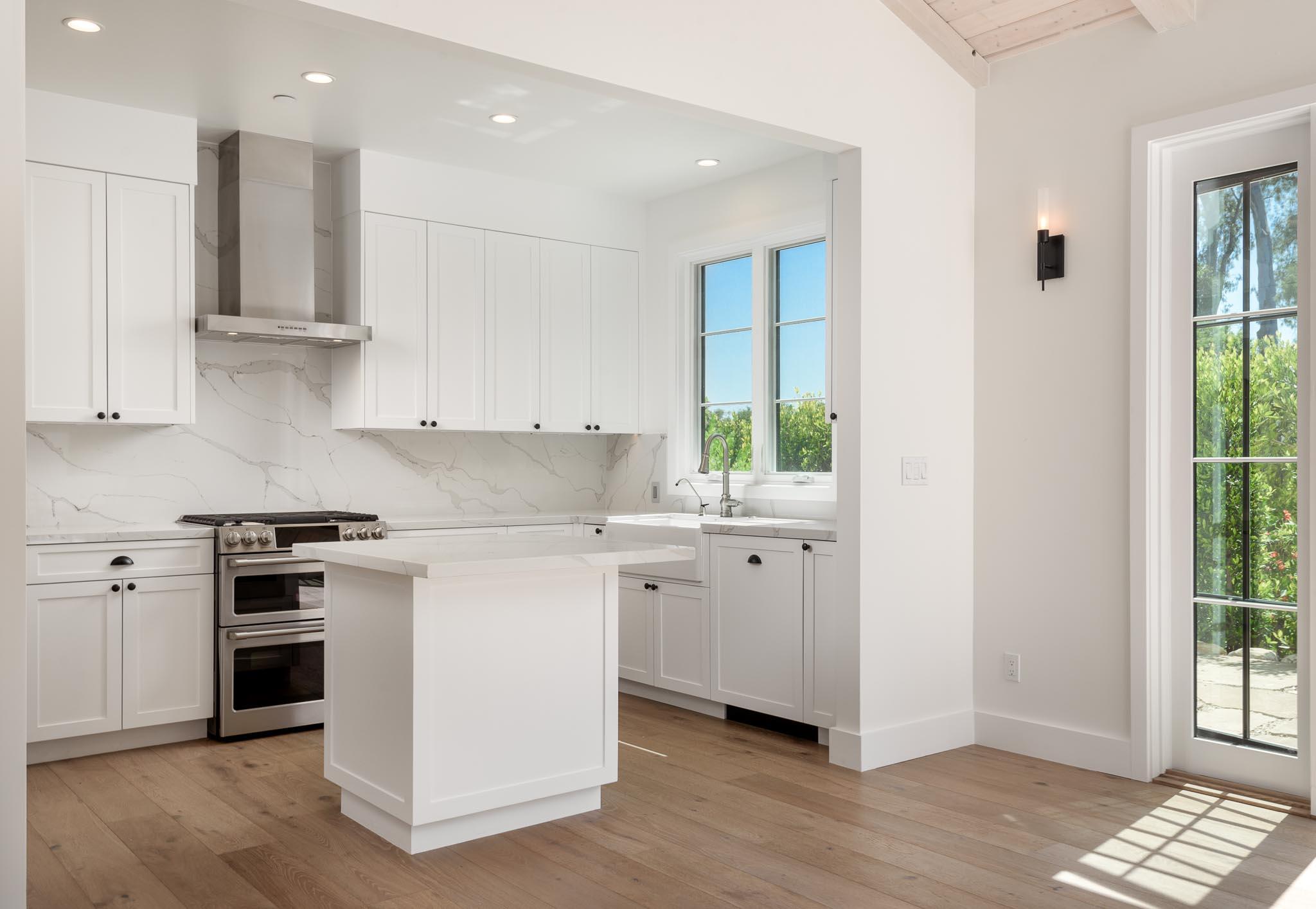765 B Hot Springs Road Montecito, CA 93108 - Photo 8 of 33 a kitchen with stainless steel appliances granite countertop a stove a sink and white cabinets with wooden floor next to windows