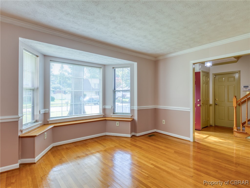 Unfurnished room featuring a wealth of natural light, a textured ceiling, and light hardwood / wood-style floors