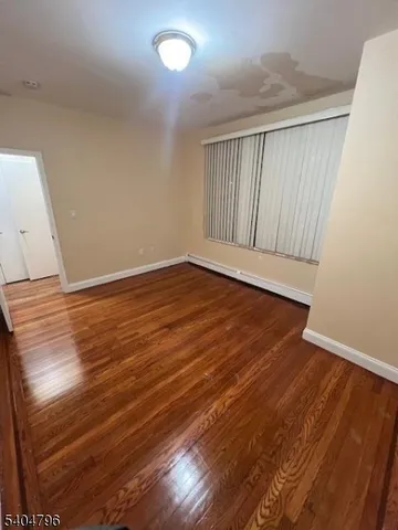 an empty room with wooden floor and windows with curtains