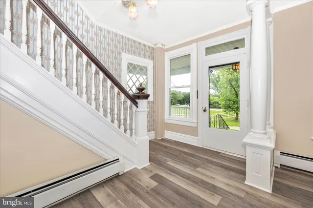 a view of an empty room with wooden floor fireplace and a window