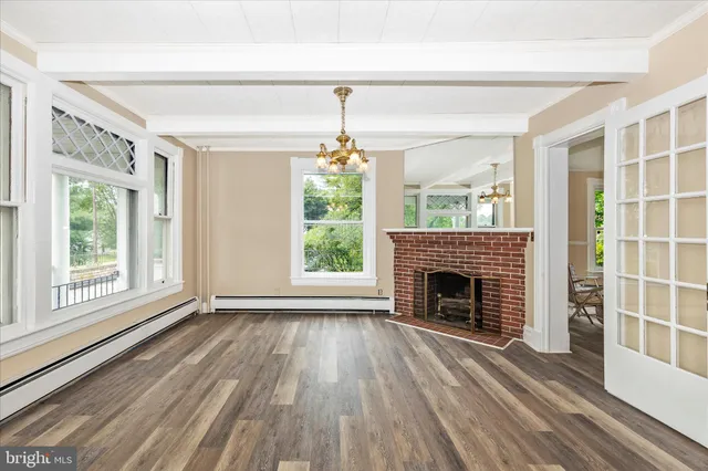 a view of a livingroom with wooden floor a fireplace and windows