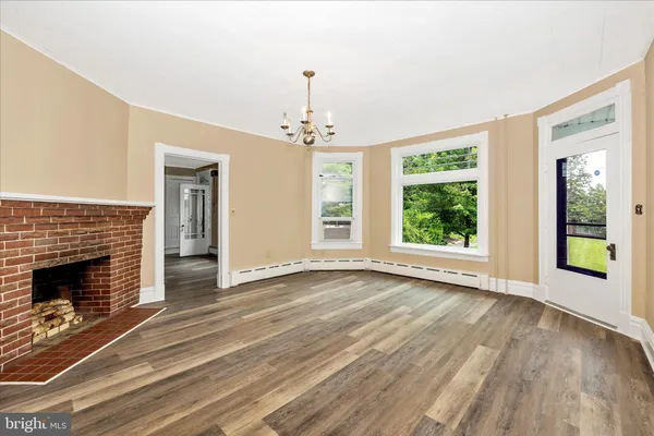 an empty room with wooden floor cabinet and windows